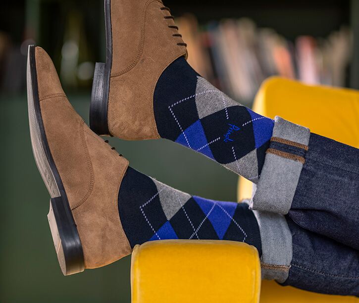 Man wearing navy and blue argyle socks with brown suede shoes