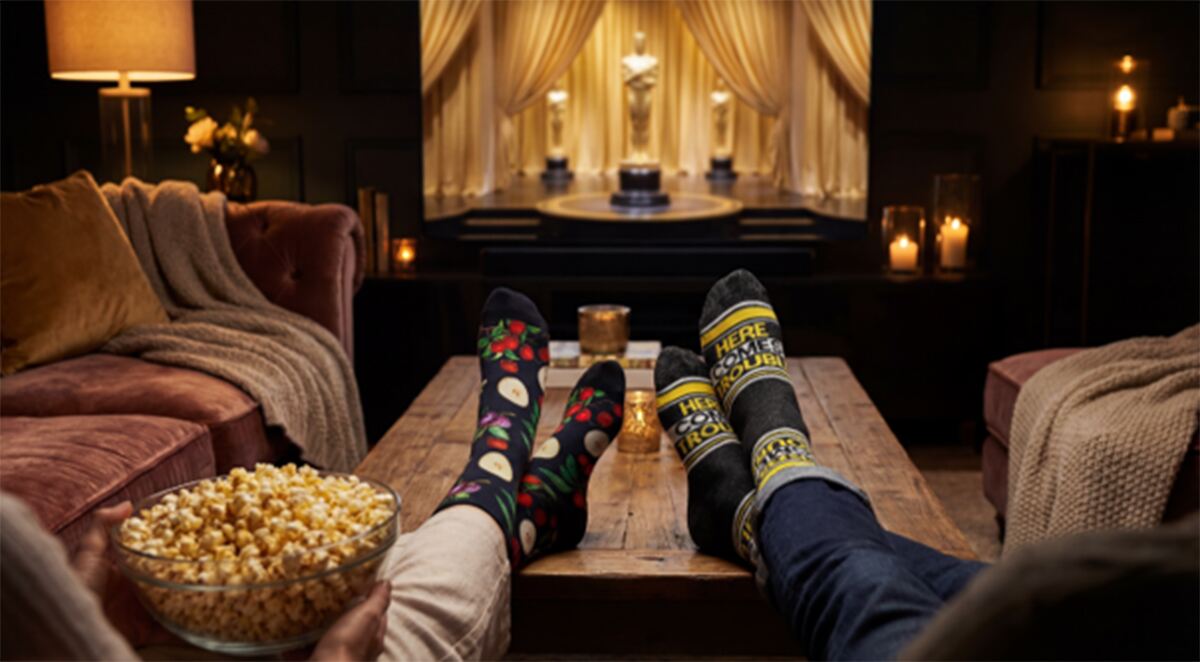 Couple in fun socks with feet up in front of TV showing The Academy Awards