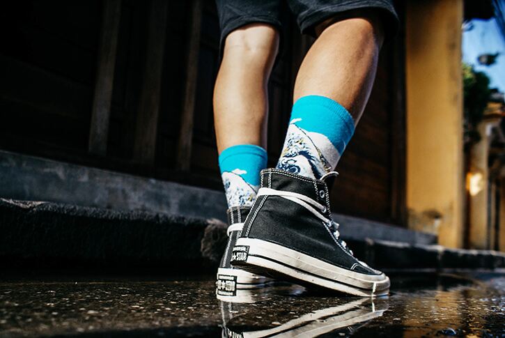 Man wearing skater shorts, graphic socks and classic black converse