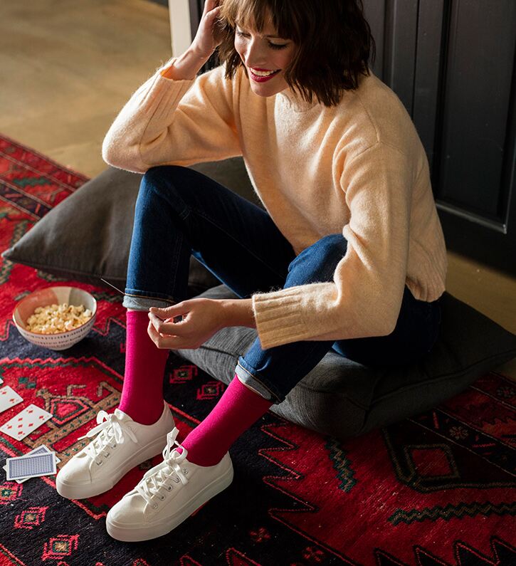 Woman in casual outfit with raspberry red socks and white trainers