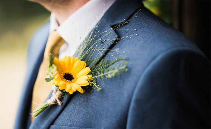 What colour tie should you wear for an interview? Man in blue suit with yellow tie and sunflower buttonhole